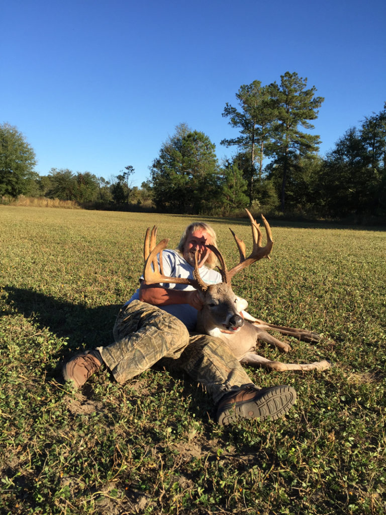 Hunter on ground posing with buck